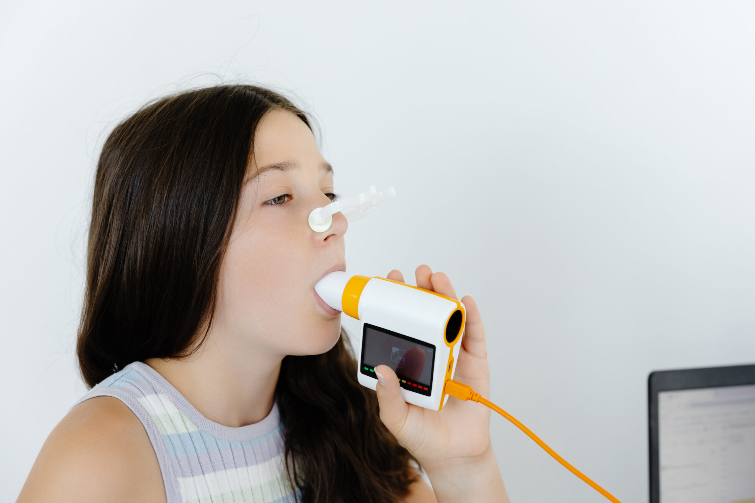 Girl testing breathing function by spirometry in doctors office. Diagnosis of respiratory function in pulmonary disease